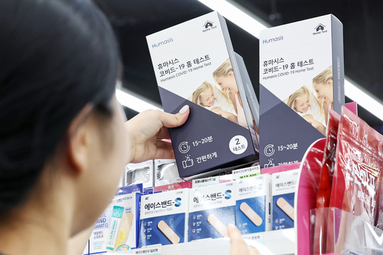 An employee displays Covid-19 self-testing kits at a convenience store in Seoul on Wednesday. [NEWS1]