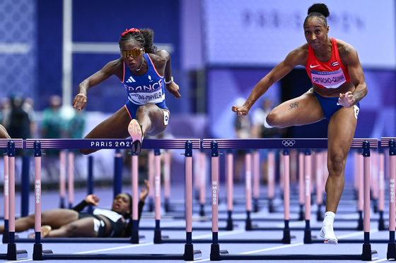 Puerto Rico's Jasmine Camacho-Quinn leads ahead of France's Cyrena Samba-Mayela as Britain's Cindy Sember reacts after falling in the women's 100-meter hurdles semifinals in Paris on Friday. [AFP/YONHAP]