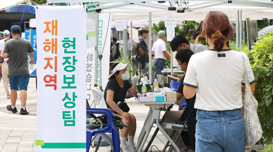 People from an apartment complex in Incheon take consultations for compensation in Incheon on Aug. 5 after a Mercedes EV burst into flames in an underground parking lot that resulted in 23 injuries. Some 500 households have suffered from electricity or water supply outages for a week. [YONHAP] 