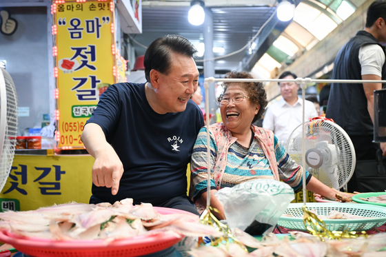 President Yoon Suk Yeol, left, chats with a fish merchant in Tongyeong Jungang Market in Tongyeong, South Gyeongsang, on Monday, the first day of his five-day summer vacation. [PRESIDENTIAL OFFICE]