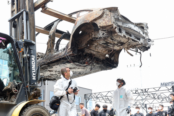 The burnt Mercedes EQE sedan is transferred for investigation in Incheon on Thursday. The EV explosion injured 23 people and damaged around 880 vehicles in the parking garage. Some 500 households have suffered from electricity outages for a week. [YONHAP] 