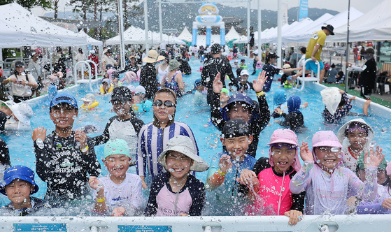 Children cool off in a swimming pool set up in Gwanghwamun Plaza in Jongno District, central Seoul, on Sunday. [NEWS1]