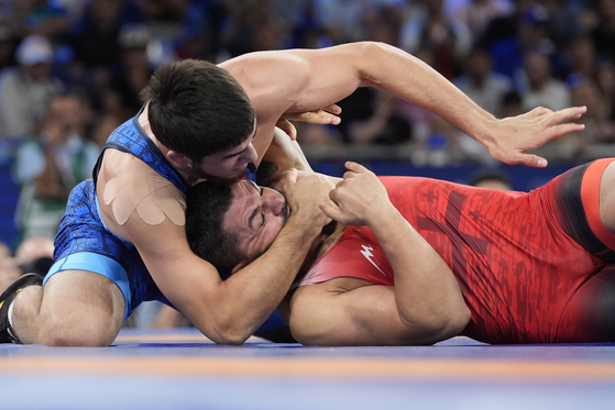 Georgia's Givi Matcharashvili, in red, and Bahrain's Akhmed Tazhudinov compete in their men's freestyle 97-kilogram final wrestling match at Champ-de-Mars Arena during the Paris Olympics in Paris on Sunday. [AP/YONHAP]