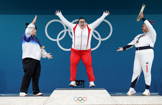 Wenwen Li of China, center, celebrates on the podium with silver medalist Park Hye-jeong of Korea and bronze medalist Emily Campbell of Great Britain after winning the women's super heavyweight weightlifting contest at the Paris Olympics on Sunday. [REUTERS/YONHAP]