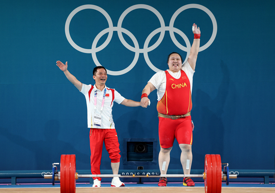 Wenwen Li of China celebrates with her coach after winning gold in the women's super heavyweight weightlifting contest at the Paris Olympics on Sunday. [REUTERS/YONHAP]