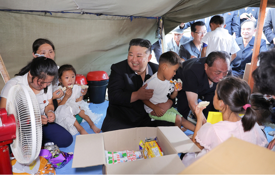 North Korean leader Kim Jong-un hugs a child during his visit to a temporary shelter in Uiju County in North Pyongan Province to offer support to flood-damaged areas, in this photo released by the state-run Korean Central News Agency on Aug. 10. [NEWS1]