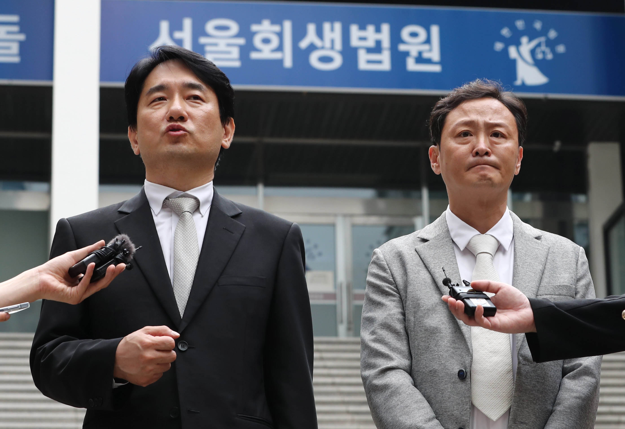 WeMakePrice CEO Ryu Hwa-hyeon, left, and TMON CEO Ryu Gwang-jin answer questions from local press in front of the Seoul Bankruptcy Court in Seocho District, southern Seoul, on Tuesday after concluding a meeting where they discussed rescue plans for the two cash-strapped e-commerce platforms.[YONHAP]