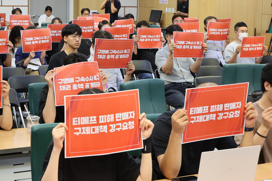 Merchants affected by delayed payments from TMON and WeMakePrice hold up signs with text demanding relief measures at the inaugural ceremony of the emergency committee created for the sellers' damage relief on Aug. 6. [YONHAP]