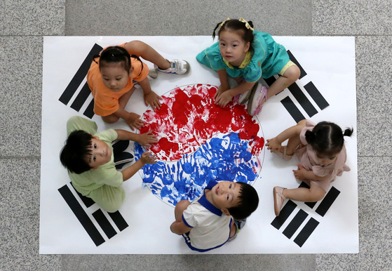 Kindergartners in Dong District, Daejeon, paint the Korean flag, Taegeukgi, with their handprints on Tuesday ahead of Liberation Day, which falls on Thursday. [NEWS1]