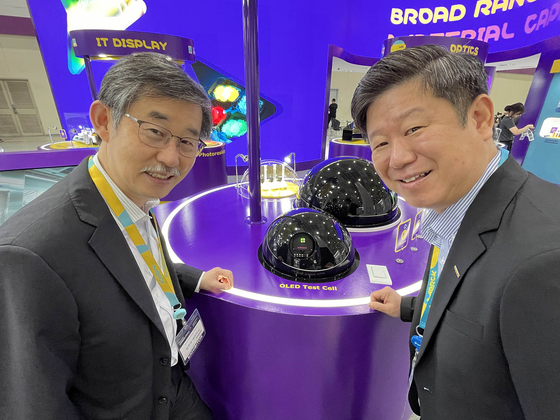 Dr. Kim Woo-kyu, managing director of Merck Korea, left, and Yun Yong-kuk, Merck Korea's country lead of display solutions, pose next to the German science and technology company's organic light-emitting diode (OLED) test cell at Korea Display Exhibition, or K-Display 2024, at Coex in southern Seoul on Wednesday. Merck participated in the show with five exhibition zones. [MERCK KOREA]