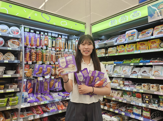 A customer poses for a photo holding CU's affordable private brand products including HEYROO Tofu Deuktem. [CU]