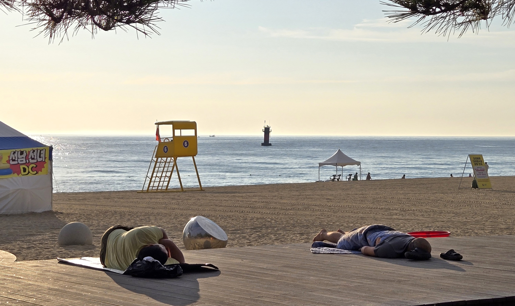 Two people sleep at a beach in Gangwon on August 7, with tropical nights having continued for 19 consecutive days. [YONHAP] 