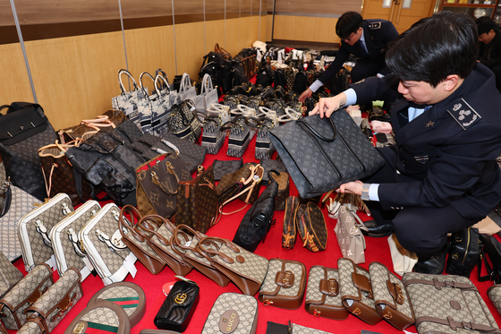 Customs officials examine counterfeit goods confiscated at the Incheon Regional Customs office in November 2023. [YONHAP]