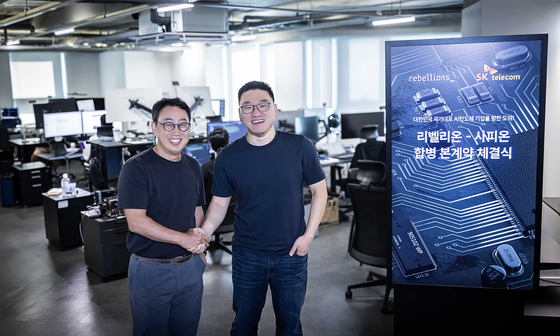 SK Telecom CEO Ryu Young-sang, left, and Park Sung-hyun, Rebellions CEO and co-founder, pose for a photo after signing a definitive merger agreement between the two companies. [SK TELECOM]