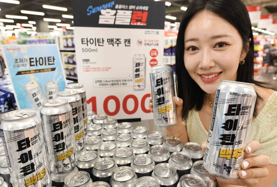 An employee holds two cans of Homeplus's ultra-cheap beer brand, Titan. [HOMEPLUS]