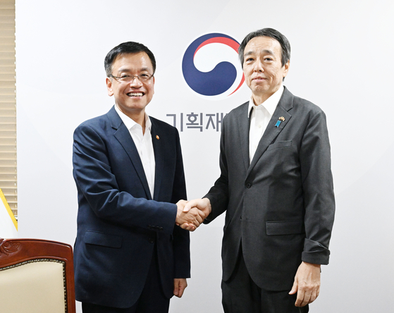 Korean Finance Minister Choi Sang-mok, left, shakes hands with Japan's new ambassador to South Korea, Koichi Mizushima, ahead of their talks in Seoul on Wednesday. [YONHAP]