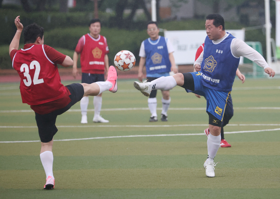 Lawmakers from rival parties put aside their differences and participate in a friendly soccer match on a field in front of the National Assembly in Yeouido, western Seoul, on Monday. (YONHAP)