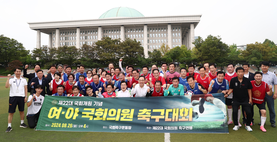 Lawmakers from rival parties take a souvenir photo after a friendly soccer match in front of the National Assembly in Yeouido, western Seoul, on Monday. (YONHAP)