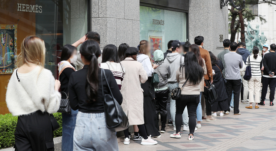 Customers wait to enter a luxury brand outlet at a department store in April 2023. [NEWS1]