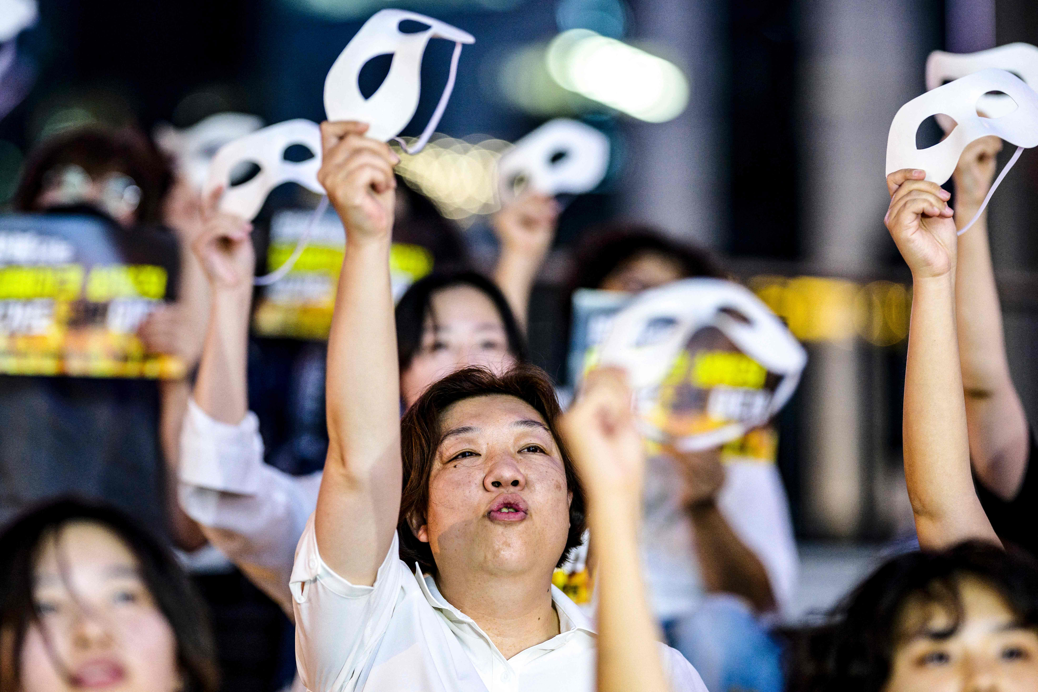 Activists hold masks and shout slogans during a protest against deepfake porn in Gangnam District, southern Seoul, on Aug. 30, 2024. (AFP/YONHAP)