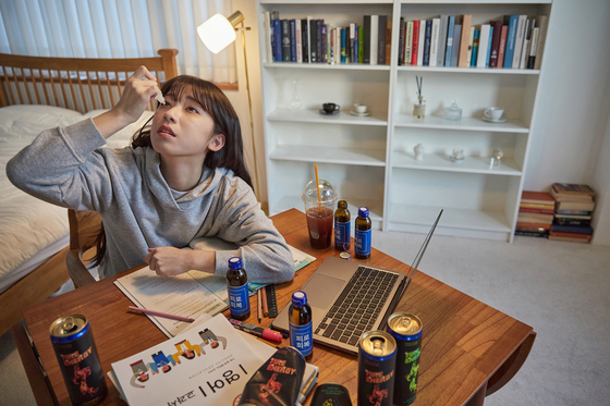 A young woman tries to keep herself awake to finish her work despite being exhausted. [GETTY IMAGE]