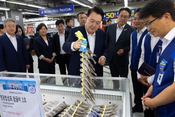 President Yoon Suk Yeol, center, checks out dried yellow corvine, or gulbi, during a visit to the Changdong branch of the Nonghyup Hanaro Mart in Dobong District, northern Seoul, on Tuesday, ahead of the Chuseok holiday later this month. [PRESIDENTIAL OFFFICE]