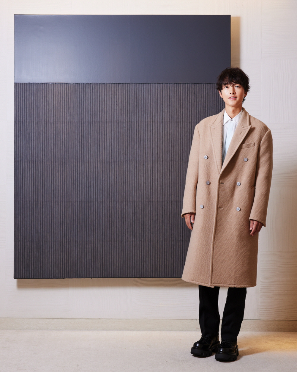 Actor Song Joong-ki stands next to one of late danseakhwa, or Korean monochrome painting, master Park Seo-bo's artwork, displayed at Louis Vuitton Maison Seoul in Gangnam Distrcit, southern Seoul. [LOUIS VUITTON]