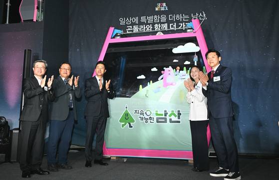 Seoul Mayor Oh Se-hoon, third from left, and officials applaud in front of the Namsan gondola cabin unveiled during the groundbreaking ceremony on Thursday. [SEOUL METROPOLITAN GOVERNMENT]