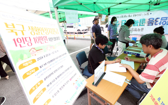 Residents receive subsidies at the Duam 3-dong Administration & Welfare Center in Buk District, Gwangju, on Wednesday. [YONHAP]