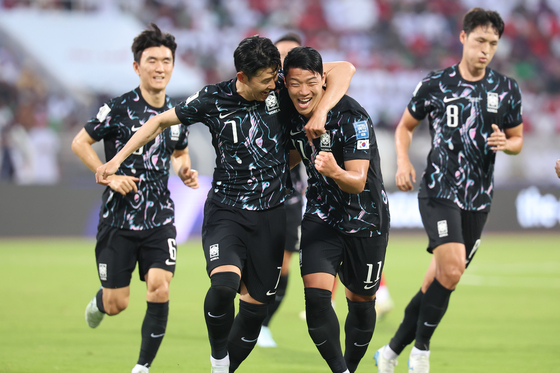 Korea's Hwang Hee-chan, center right, celebrates scoring with Son Heung-min during a 2026 World Cup qualifier against Oman at Sultan Qaboos Sports Complex in Oman on Tuesday. [YONHAP]