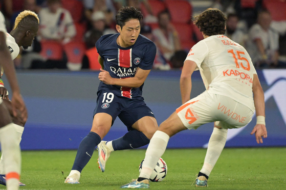 Paris Saint-Germain's Lee Kang-in, left, fights for the ball with Montpellier's midfielder Gabriel Bares during the Ligue 1 match at The Parc des Princes Stadium in Paris on Aug. 23. [AFP/YONHAP] 