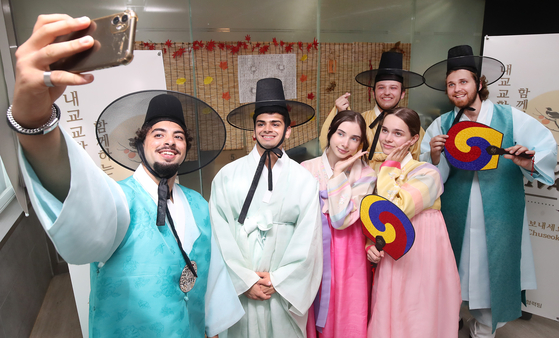 Foreign students dressed in hanbok, or traditional Korean clothing, take photos at a Chuseok experience center set up on the campus of Yeungnam University in Gyeongsan, North Gyeongsang, on Thursday afternoon. [NEWS1]