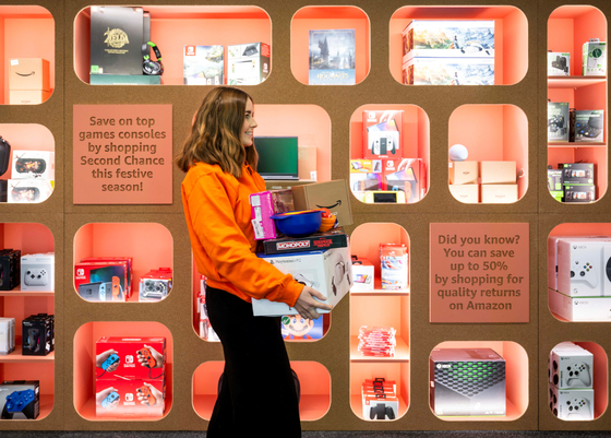 A staff member carries products at the Second Chance Store, a shop selling refurbished products from Amazon's Second Chance programs in central London, Britain. [REUTERS/YONHAP]