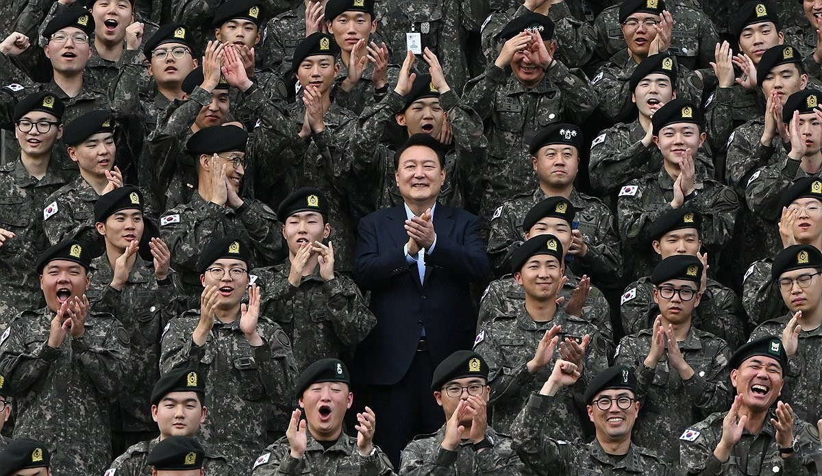 President Yoon Suk Yeol, center, poses for a picture with soldiers on Tuesday, at the 15th Infantry Division in Gangwon. Second row, third from right, RM of BTS is seen clapping. [PRESIDENTIAL OFFICE]