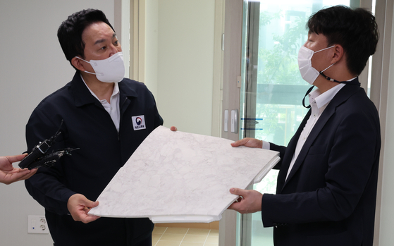 Former Land Minister Won Hee-ryong, left, listens to an explanation about sound-absorbing mats at a state-supplied apartment in Seoul in August 2022. [YONHAP] 