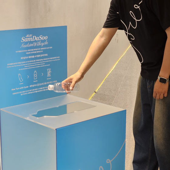 A person throws away a plastic bottle into a collection box set up by Jeju Samdasoo at DDP during Seoul Fashion Week in September. [SEOUL METROPOLITAN GOVERNMENT]