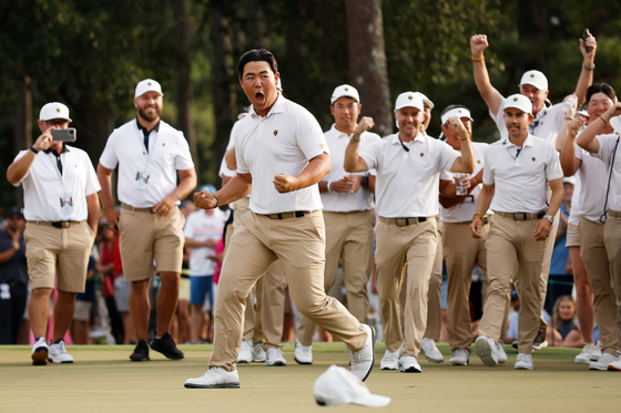 Tom Kim and the International Team celebrate his hole-winning putt to win match 1 with teammate Kim Si-woo against Patrick Cantlay and Xander Schauffele of the United States during Saturday afternoon four-ball matches on day three of the 2022 Presidents Cup in Charlotte, North Carolina on Sept. 24, 2022.  [GETTY IMAGES]