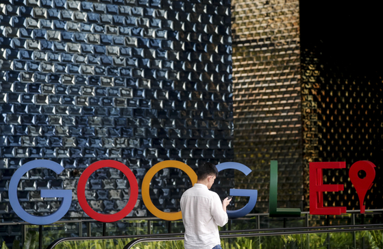 A man uses his mobile phone while walking past the Google logo in Singapore in 2019. [EPA]