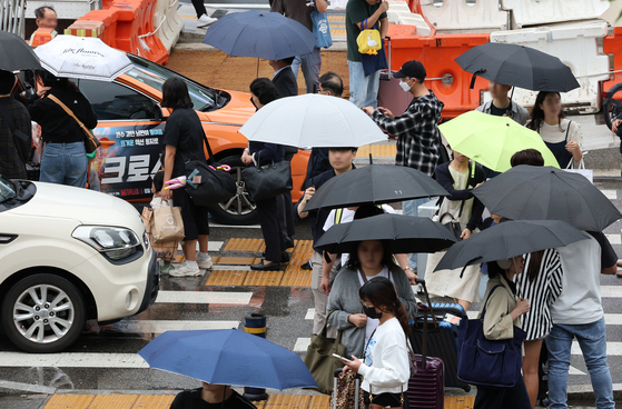 People with umbrellas walk near Seoul Station in Jung District, central Seoul, as heavy rain batters the country on Saturday. [NEWS1]