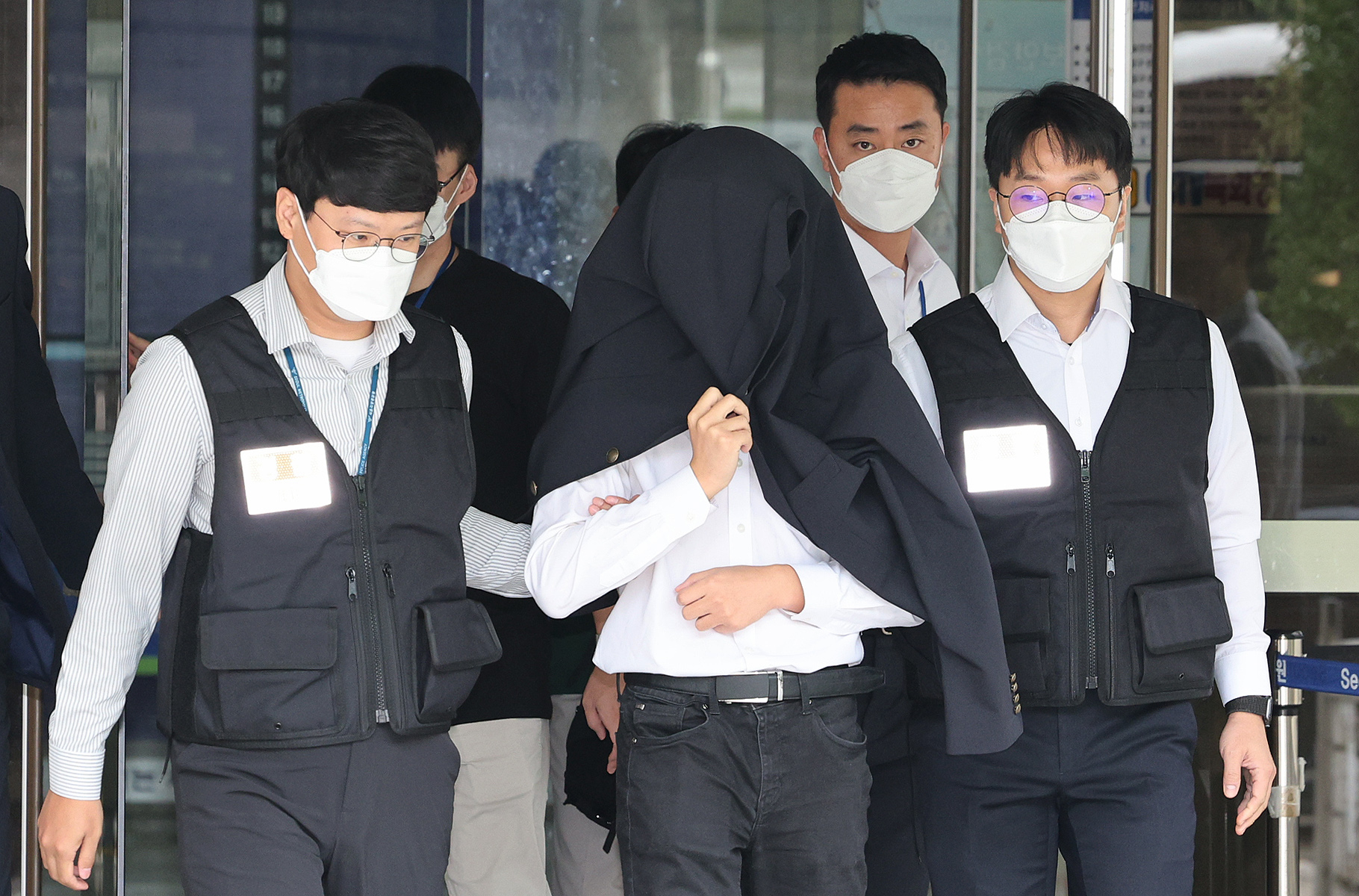 A junior doctor, identified only by his surname Jeong, is escorted by police out of the Seoul Central District Court in Seocho District, southern Seoul, after attending his arrest warrant review on Friday. The court later approved an arrest warrant against Jeong, who is accused of compiling a list of junior doctors who have not joined their colleagues' mass walkout to protest the government's plan to increase annual medical recruitment. [NEWS1]