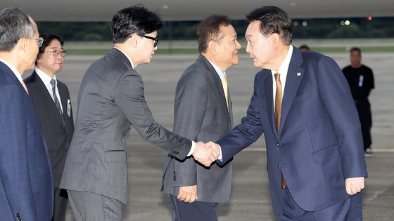 President Yoon Suk Yeol, right, is greeted by People Power Party Chairman Han Dong-hoon, left, as he arrives at Seoul Air Base in Seongnam, Gyeonggi, Sunday morning, ending a four-day official visit to the Czech Republic. [JOINT PRESS CORPS]