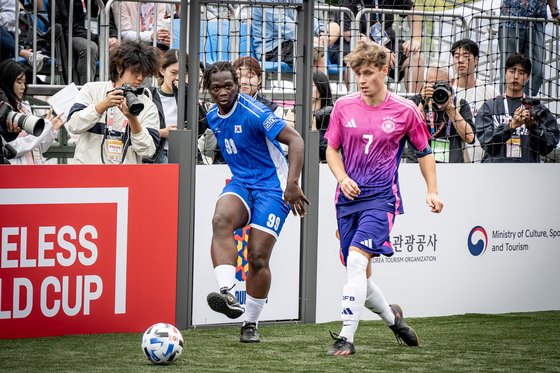 Korea's Fossi Wandji, left, competes for the ball during the opening game of the 2024 Homeless World Cup against Germany at Hanyang University in eastern Seoul on Saturday.  [HOMELESS WORLD CUP]