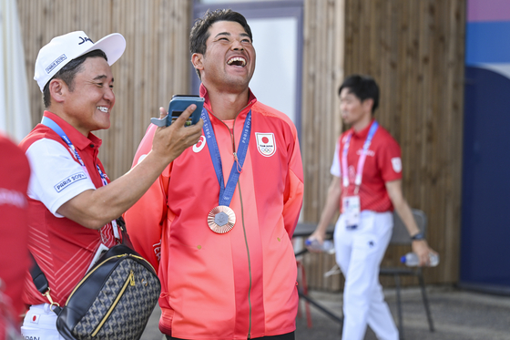 Hideki Matsuyama of Team Japan smiles with team coach Shigeki Maruyama after winning the bronze medal in the final round of the Olympic men's golf competition at the 2024 Paris Olympics on Aug. 4.  [GETTY IMAGES]