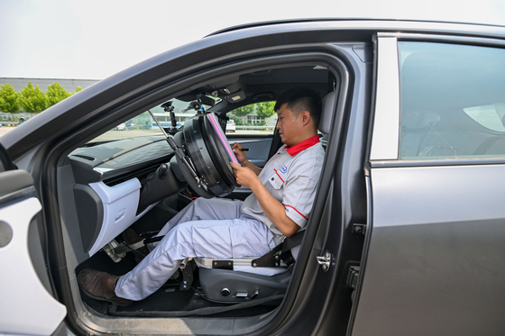 Intelligent connected vehicle tester Zhang Cheng records the test data of a vehicle at an automobile inspection center in Tianjin, north China, on June 19. [XINHUA/YONHAP]