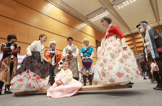 Visitors to the 2023 Korea-Kapan Hanmadang Festival in Gangnam District, southern Seoul, experience traditional Korean games while wearing hanbok. [YONHAP]