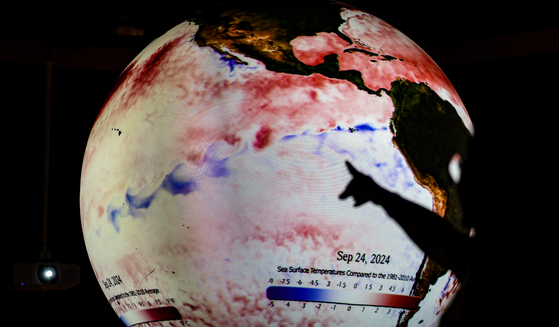 A visitor to the Daegu National Science Museum views a display tracking abnormal temperatures worldwide due to La Niña on Friday. [YONHAP]