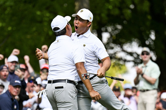 Tom Kim of the International Team, right, celebrates with teammate Kim Si-woo after a birdie on the 14th hole during Four-Ball matches on day three of the 2024 Presidents Cup at The Royal Montreal Golf Club on Saturday in Montreal, Quebec. [GETTY IMAGES]