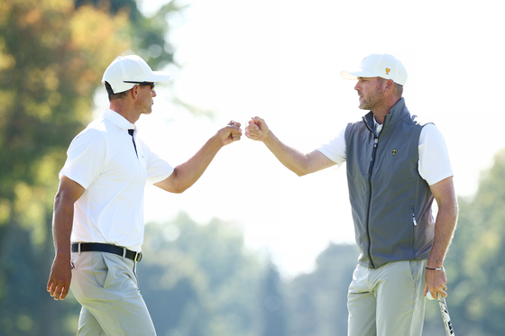 Adam Scott of Australia,, left, and Taylor Pendrith of Canada and the International Team celebrate on the third green during Saturday Afternoon Foursomes on day three of the 2024 Presidents Cup at The Royal Montreal Golf Club on Saturday in Montreal, Quebec, Canada. [GETTY IMAGES]