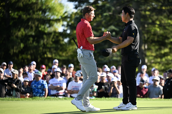 Sam Burns and Tom Kim shake hands on the 18th hole green after their match on day four of the 2024 Presidents Cup at The Royal Montreal Golf Club in Montreal, Quebec on Sunday.  [GETTY IMAGES]