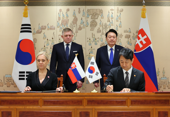 President Yoon Suk Yeol, right back, and Slovak Prime Minister Robert Fico, left back, watch Trade Minister Ahn Duk-geun, right front, and Denisa Sakova, Slovak deputy prime minister and minister of economy, left front, sign memorandums of understanding (MOU) during a signing ceremony in Seoul Monday. [JOINT PRESS CORPS]